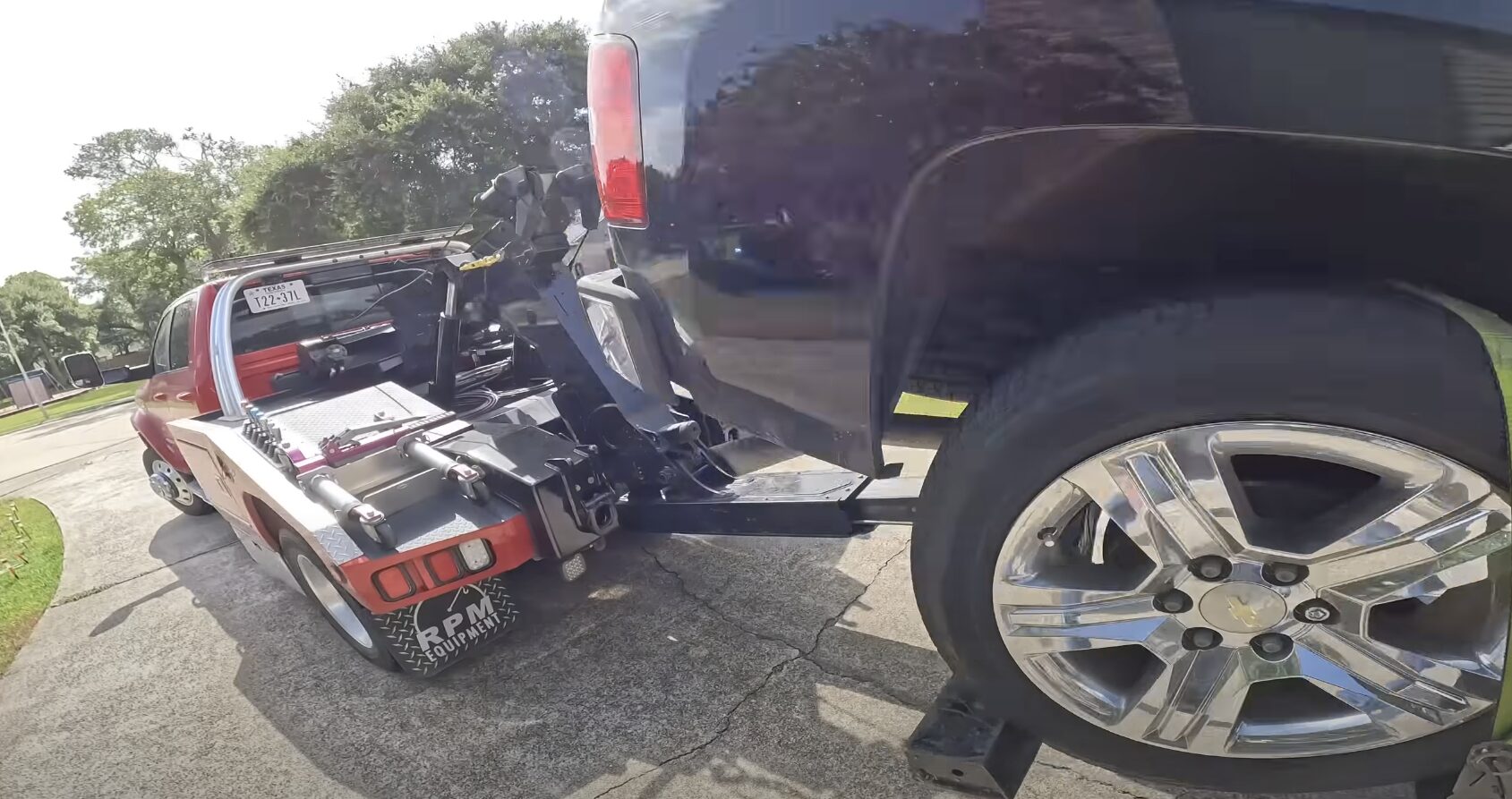 Professional tow truck with extended boom loading damaged pickup truck showing heavy-duty towing capabilities
