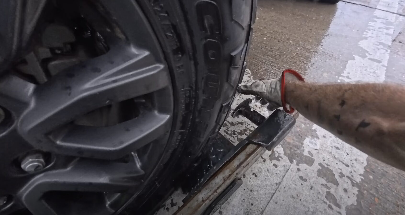 Close-up view of car tire secured with chains on flatbed tow truck showing proper vehicle securing methods